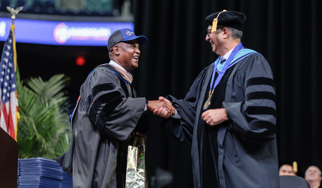 Photo of two people shaking hands at a commencement ceremony.