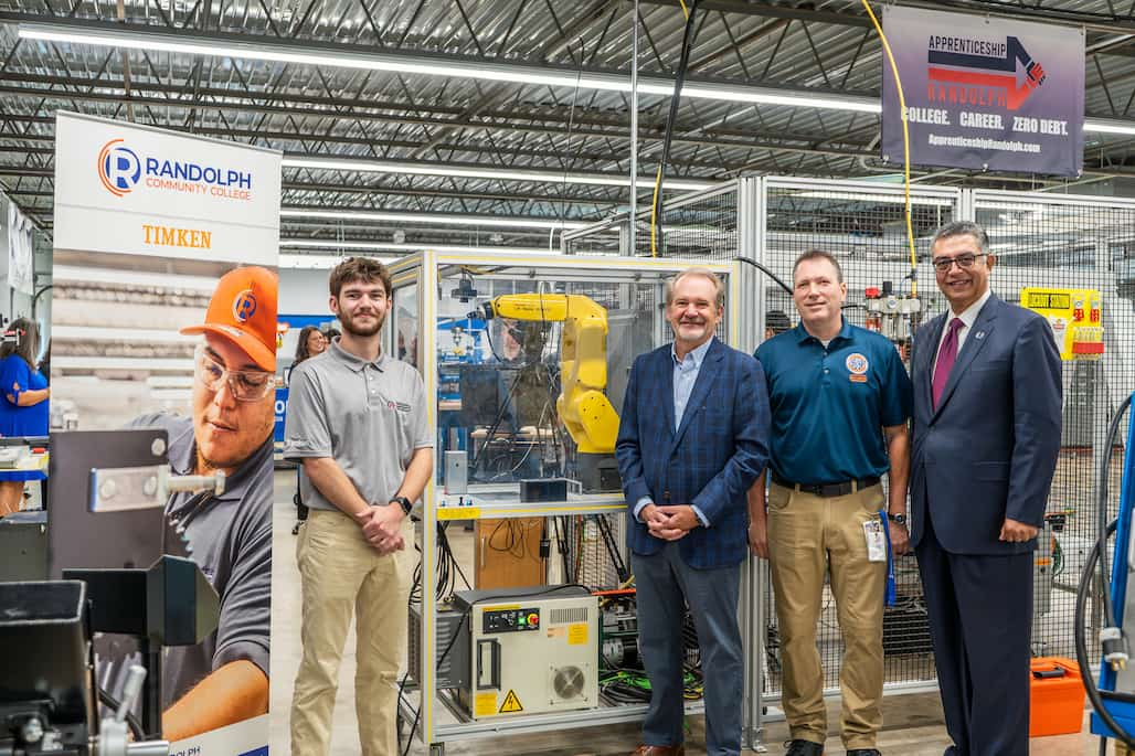 Photo of four people standing for a photo in a manufacturing center.