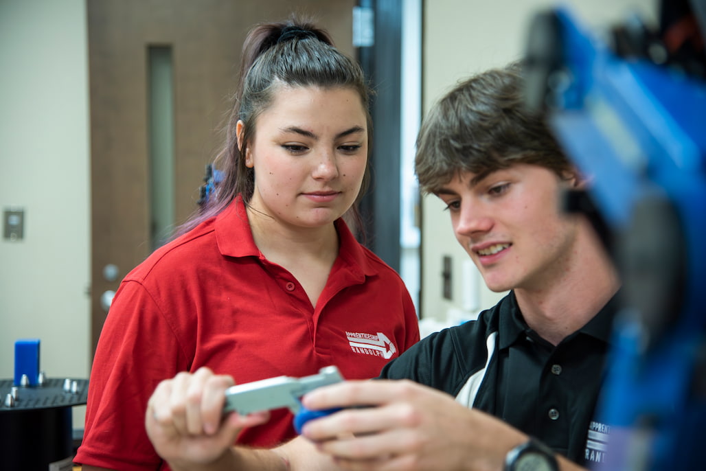 Photo of two apprentices using a micrometer to measure a part in class.