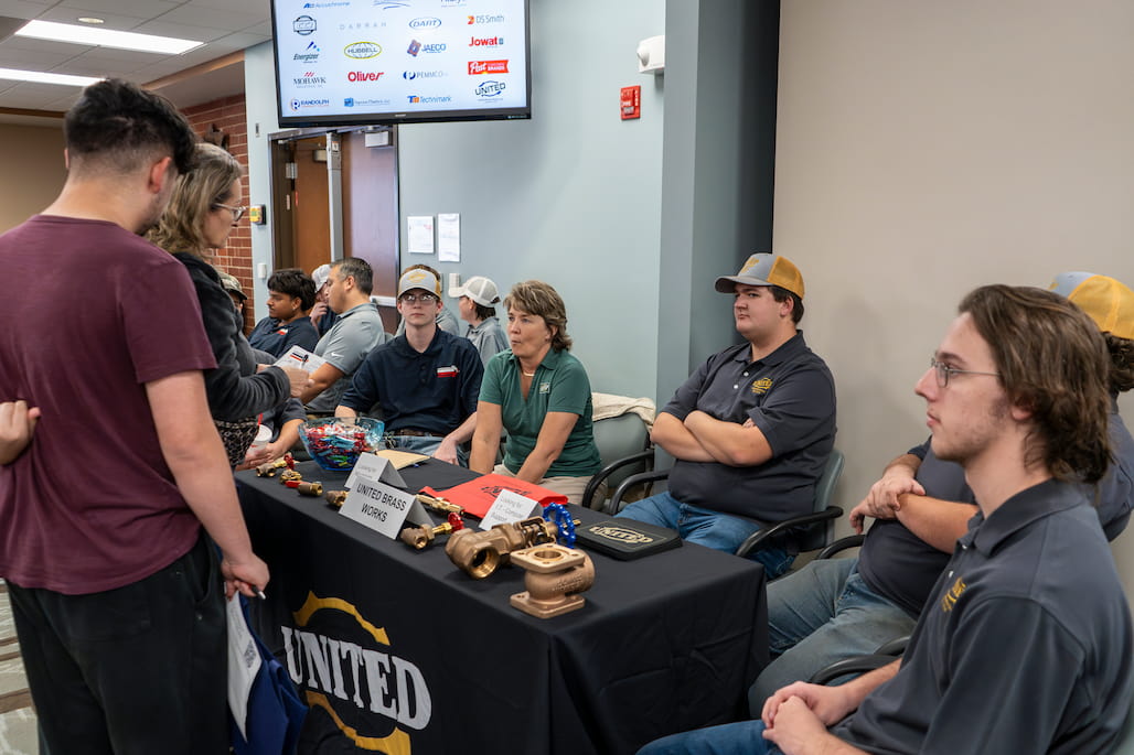 Photo of a group of people sitting at a table talking to people who are standing.