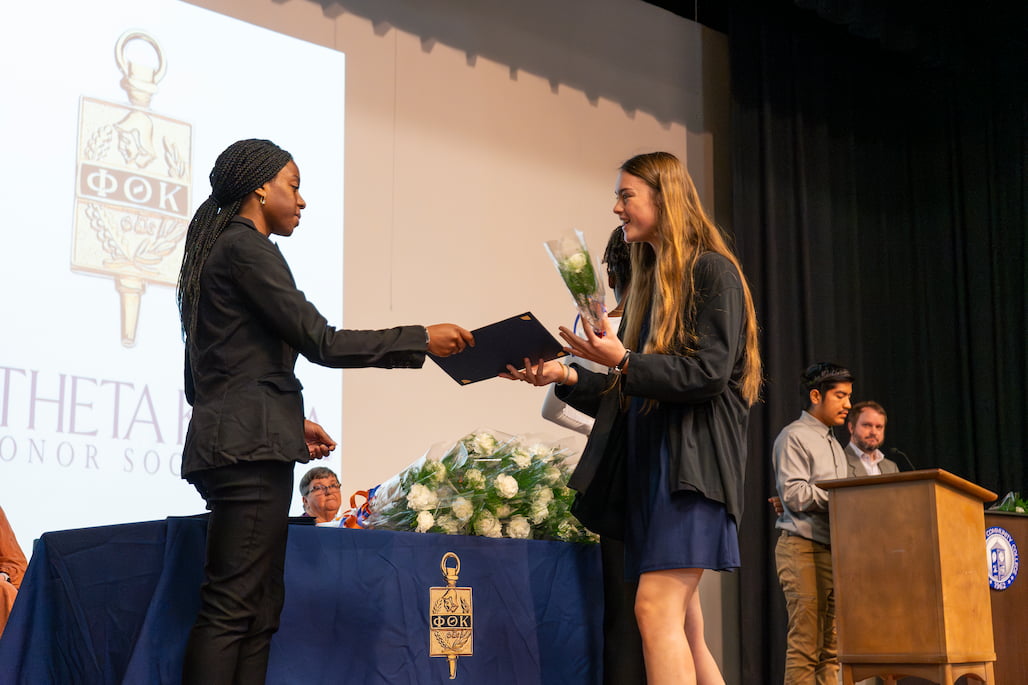 Photo of a person receiving a certificate from another person on the stage in Randolph Community College's LRC Auditorium.